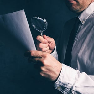 Man looks at paper with magnifying glass
