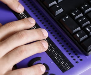 Hands using a braille keyboard.