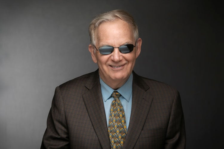 Ed Marquette is shown wearing sunglasses, a suit and a smile.