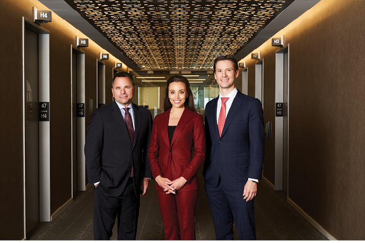 Two men flank a woman, all are wearing business suits