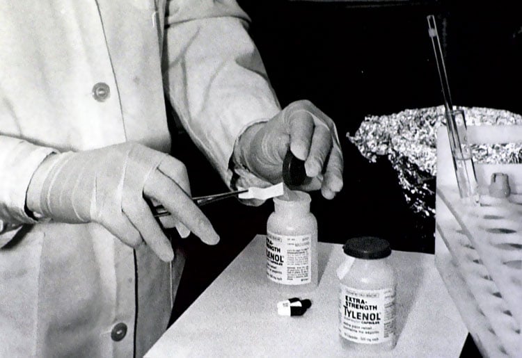 A tecnician in a labcoat takes samples from Tylenol bottles