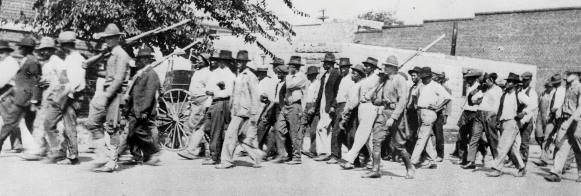 National Guard troops escort unarmed Black men to the detention center at Convention Hall after the Tulsa Race Massacre.
