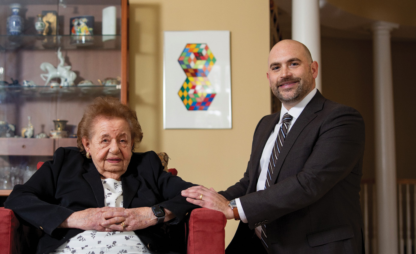 A man and woman are sitting on a red couch. The man is wearing a suit and tie. 