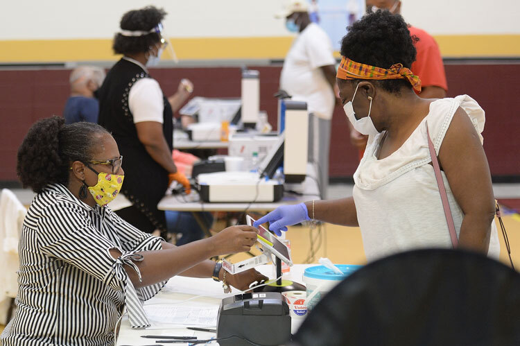 Poll worker assists a voter in St. Louis. Both are masked.