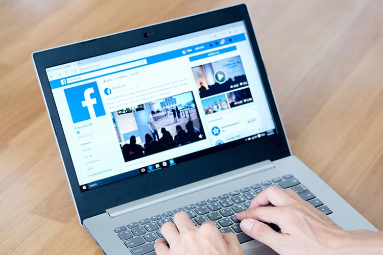 Facebook on computer with hands on keyboard