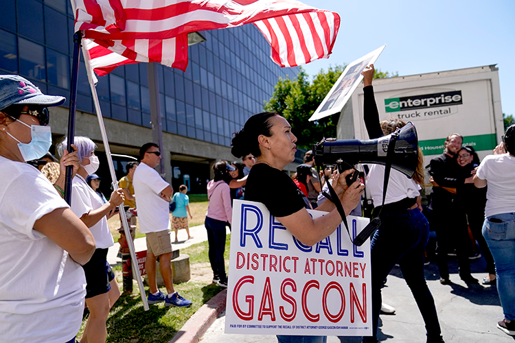People carrying signs advocating for George Gascon's recall