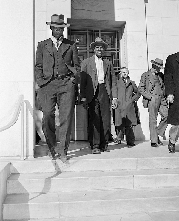 Men descend a staircase in a black-and-white historical photo