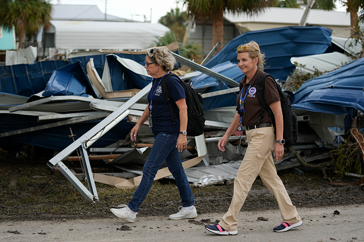 Two women walk through debris