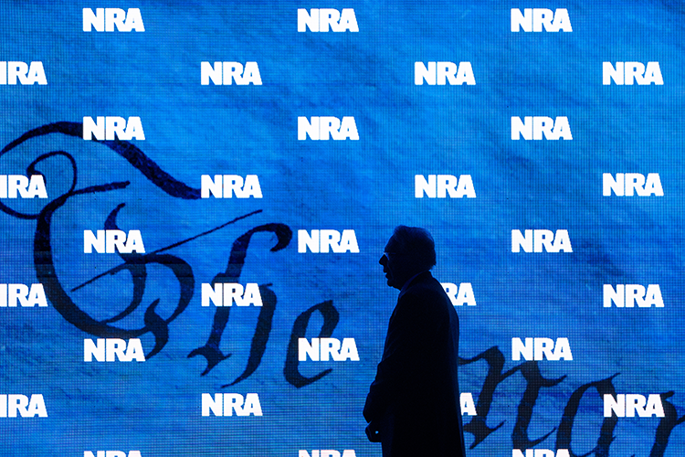 Man in silhouette with the constitution and NRA symbols on screen