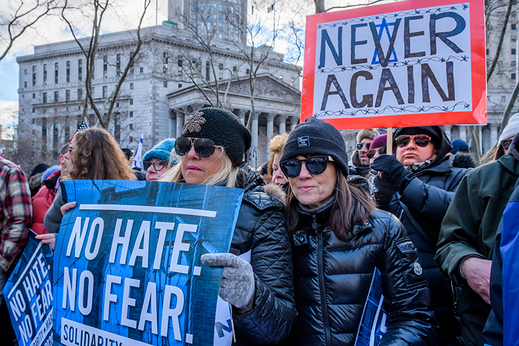 Marchers at a protest hold signs against hate and antisemitism