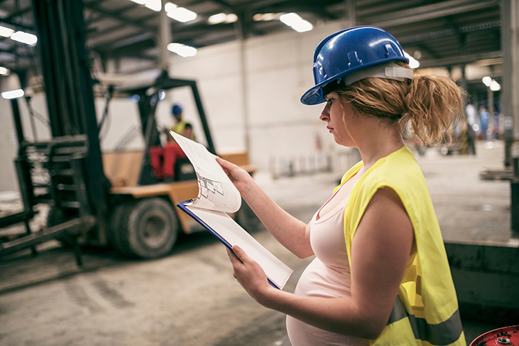 Pregnant woman in a hard hat at a construction site