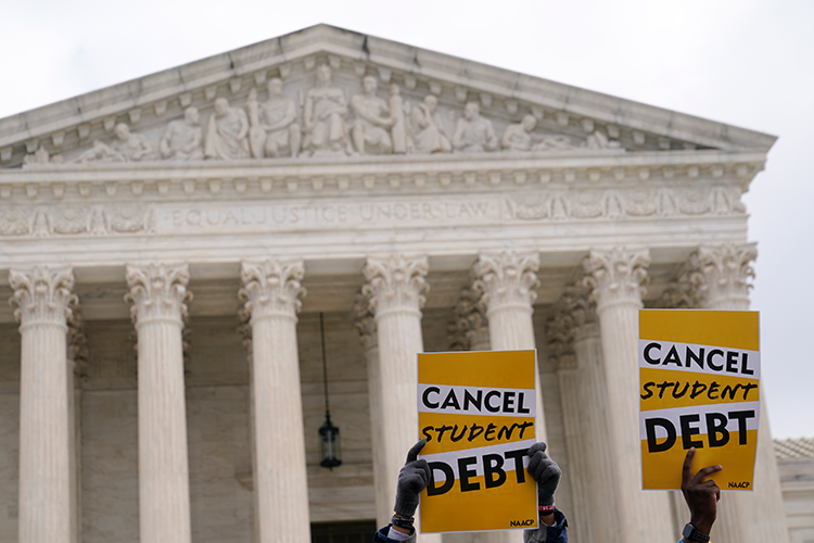 Signs in favor of student debt relief being held up in front of the Supreme Court building