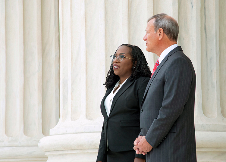 Justice Ketanji Brown Jackson and Chief Justice John Roberts stand on the steps of the Supreme Court Building