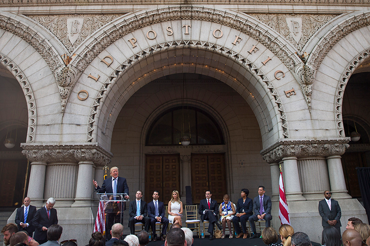 Donald Trump speaks at a podium in front of the entrance to the Old Post Office
