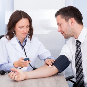 doctor taking businessman's blood pressure