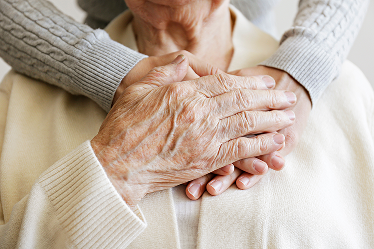 An elderly person's hands being clasped