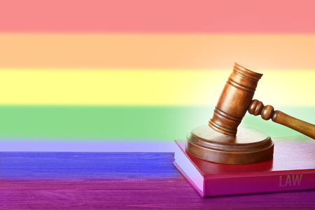 Rainbow flag and a gavel sitting on a law book.