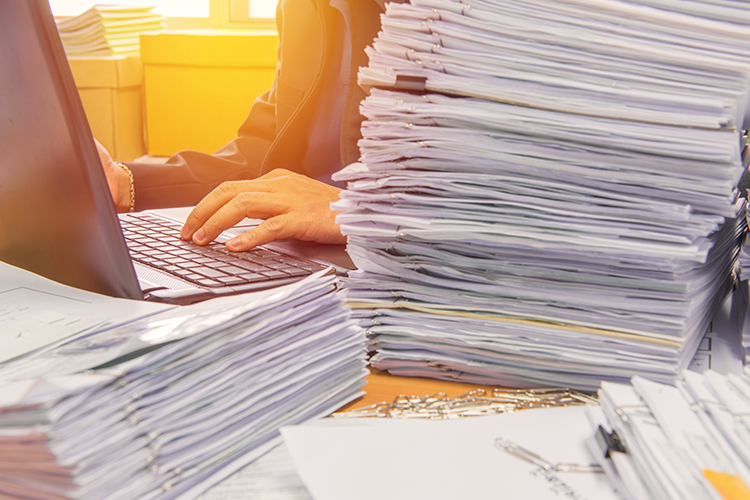 Piles of paperwork overwhelming a desk