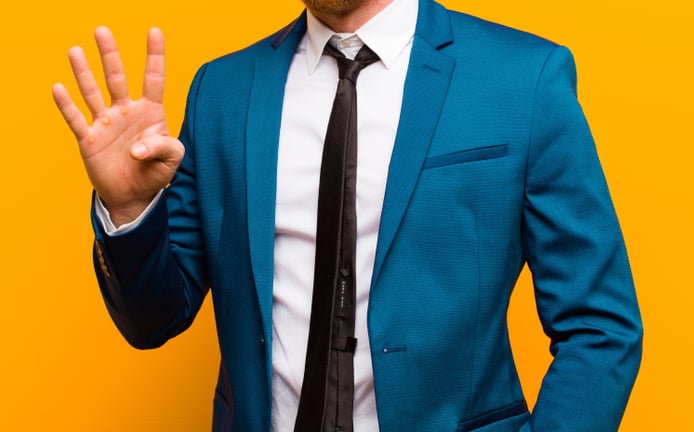 man holding up four fingers in suit