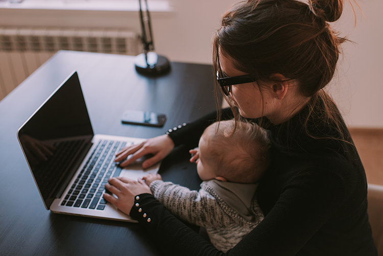 Working mother at a laptop with a baby